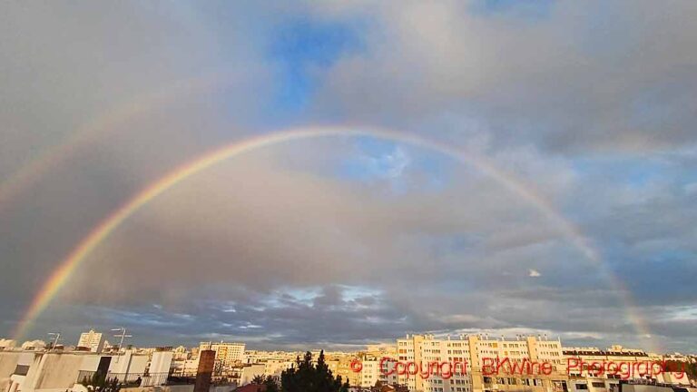 A full double rainbow in the cloudy sky after a heavy rainstorm