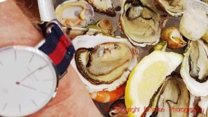 A wristwatch showing 2 PM (14.00) and a plate of oysters